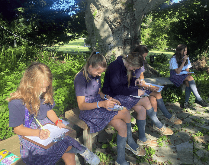 Upper school girls study outside on a beautiful campus