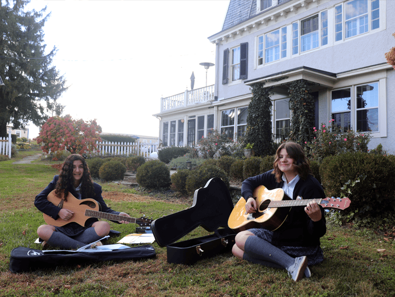 Students playing music outside on beautiful campus grounds