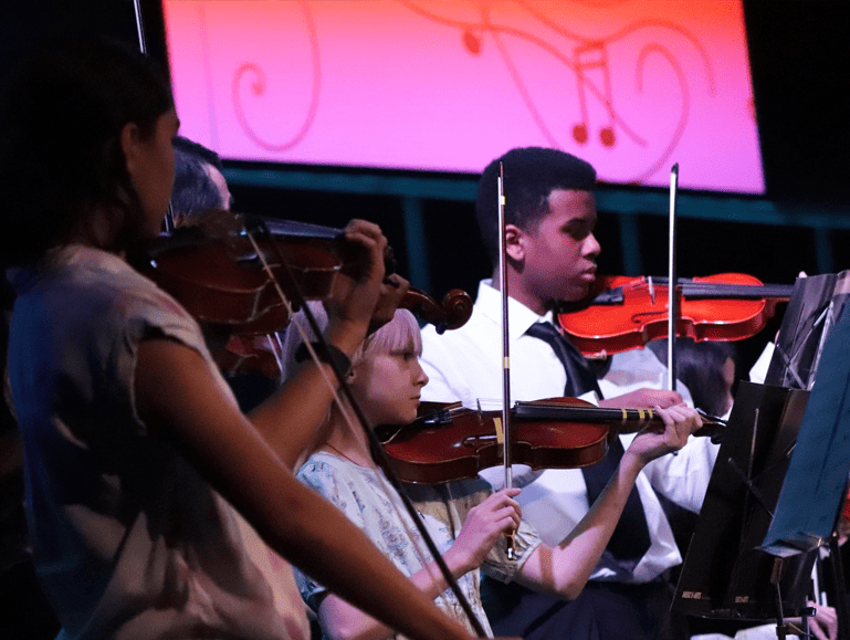 Students playing violins and other instruments during a yearly concert