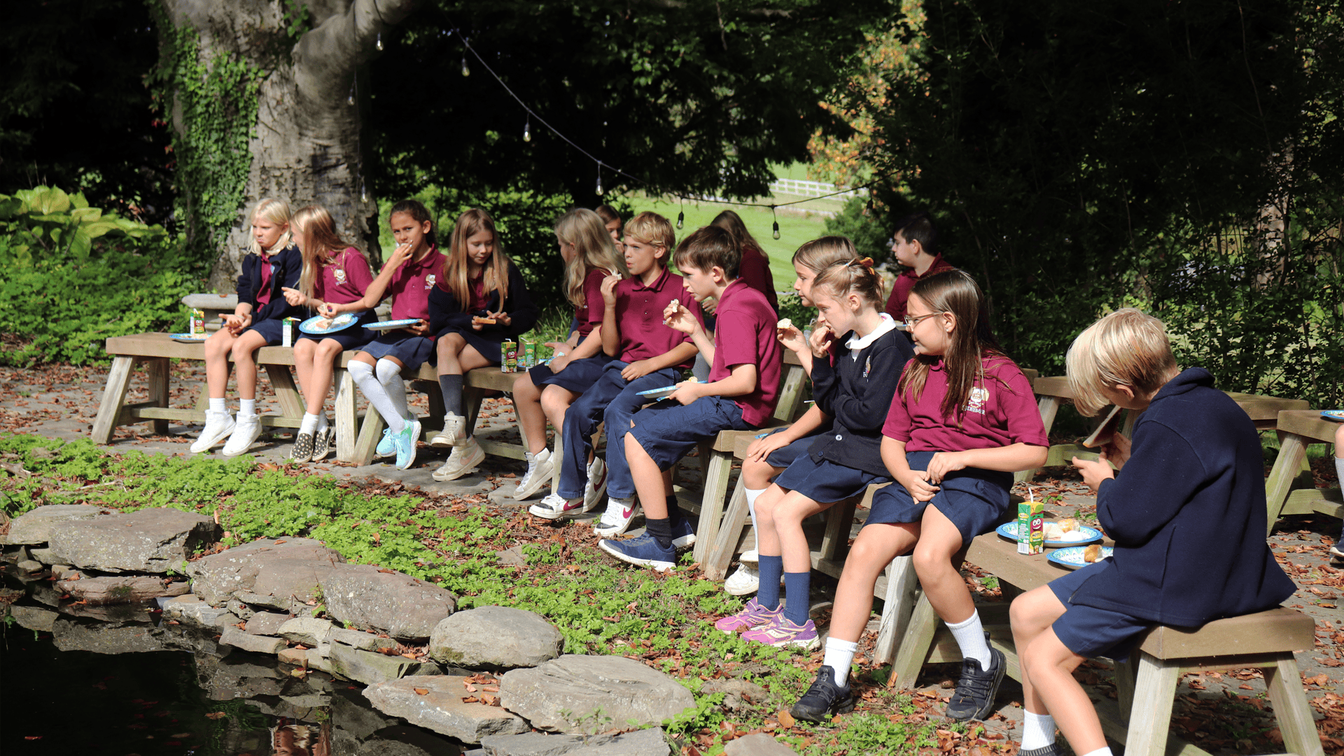 Beautiful Redeemer school grounds with students studying by a pond