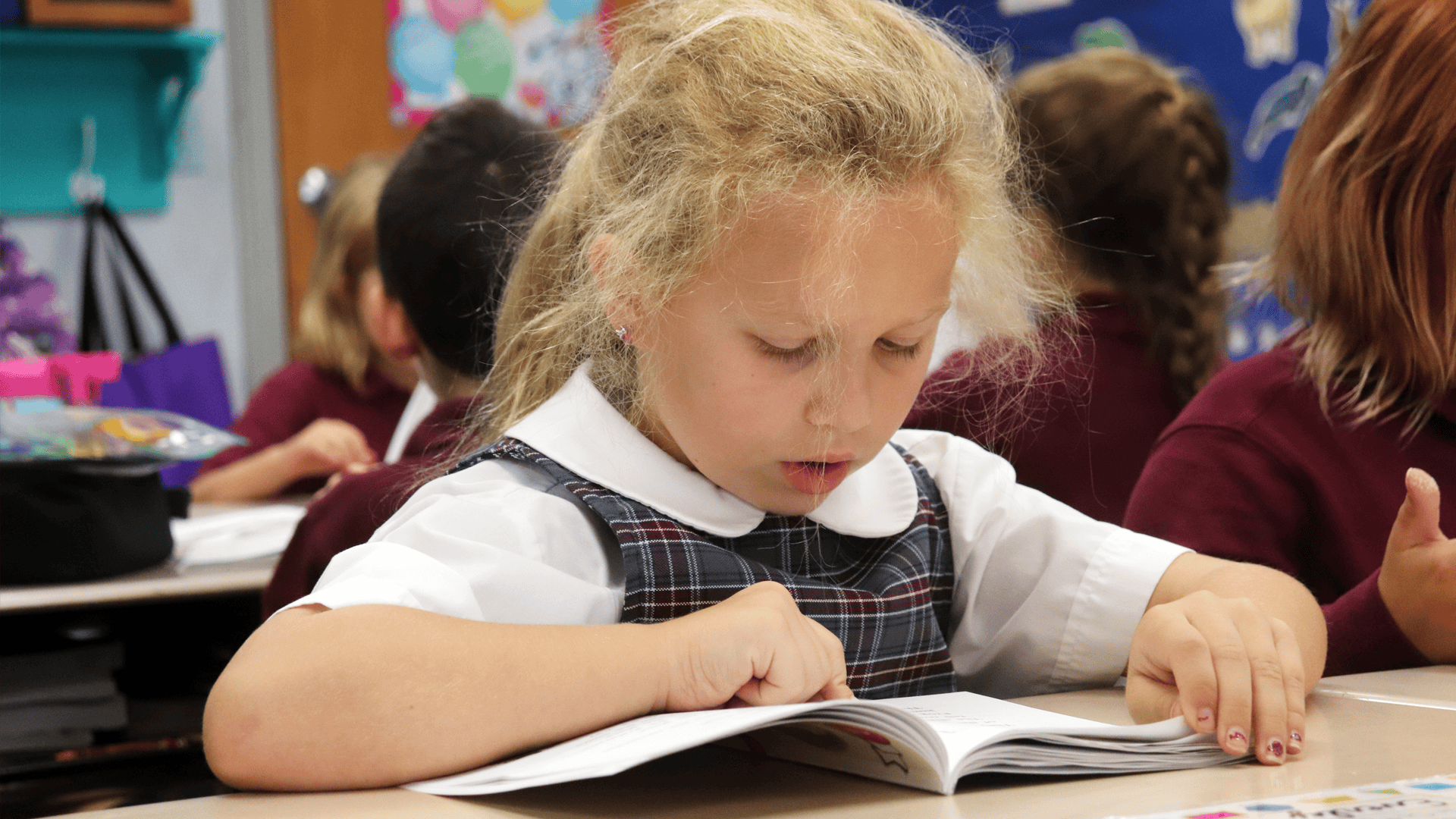 Young elementary private school girl student reading an advanced level book